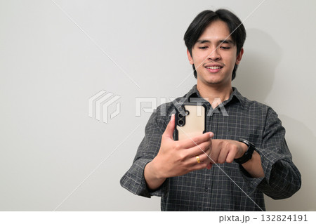 Portrait of handsome Young Asian Thai man using phone against white background Portrait of handsome Young Asian Thai man using phone against white background 132824191