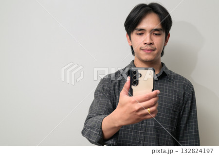 Portrait of handsome Young Asian Thai man using phone against white background Portrait of handsome Young Asian Thai man using phone against white background 132824197
