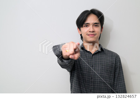 Portrait of handsome Young Asian Thai man pointing finger against white background Portrait of handsome Young Asian Thai man pointing finger against white background 132824657