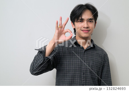Portrait of handsome Young Asian Thai man making OK sign gesture against white background Portrait of handsome Young Asian Thai man making OK sign gesture against white background 132824693