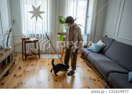 Happy young woman spending weekend time at home with pet, playing with domestic cat in living room. Happy young woman spending weekend time at home with pet, playing with domestic cat in living room. 132824977