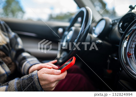Woman car driver scrolling social media online on smartphone, answers messages, reads news on phone. 132824994