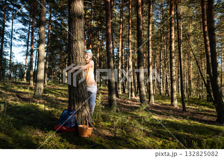 Content woman embracing tree during harvesting in woods. Peaceful female Earth bonding, green lover Content woman embracing tree during harvesting in woods. Peaceful female Earth bonding, green lover 132825082