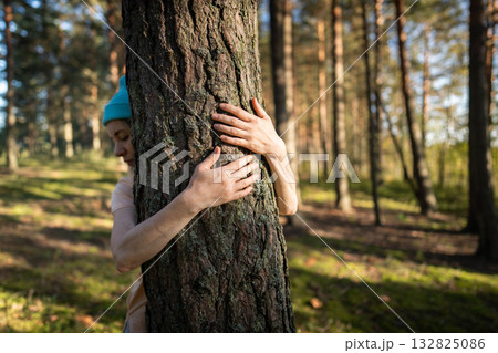 Woman hands hugging tree trunk with love in forest. Protecting nature, sustainable welfare Woman hands hugging tree trunk with love in forest. Protecting nature, sustainable welfare 132825086