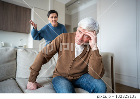 Furious wife shouts at husband while he wearies from relentless criticism on sofa. Nagging stress Furious wife shouts at husband while he wearies from relentless criticism on sofa. Nagging stress 132825135