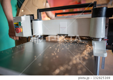 Skilled craftsman working with wood on planer thicknesser jointer, preparing furniture materials 132825169