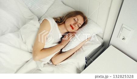 Woman sleeping lying in bed on white soft comfortable pillow in bedroom at home 132825328