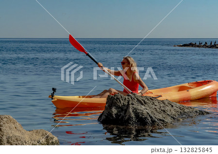 Woman, kayak, ocean. Woman paddling an orange kayak in the clear blue sea enjoying summer leisure. 132825845