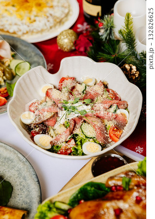 Festive salad with roast beef, quail eggs, lettuce and parmesan on a holiday table Festive salad with roast beef, quail eggs, lettuce and parmesan on a holiday table 132826625