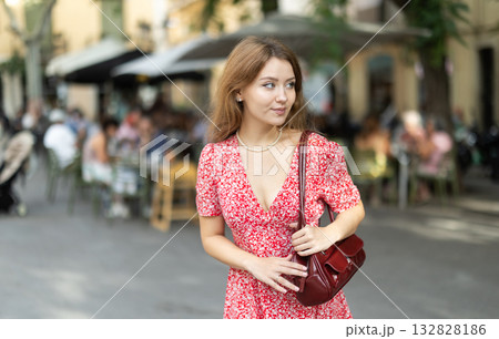 Woman in dress looking around city street on summer day 132828186