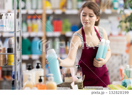 Sales girl places shampoo and shower gel on the shelves of supermarket Sales girl places shampoo and shower gel on the shelves of supermarket 132828199