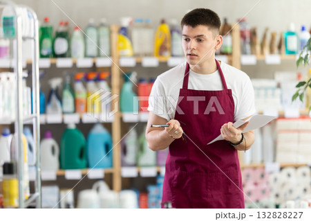 Male seller makes notes on paper - keeps track of the receipt and expenditure of goods in supermarket Male seller makes notes on paper - keeps track of the receipt and expenditure of goods in supermarket 132828227