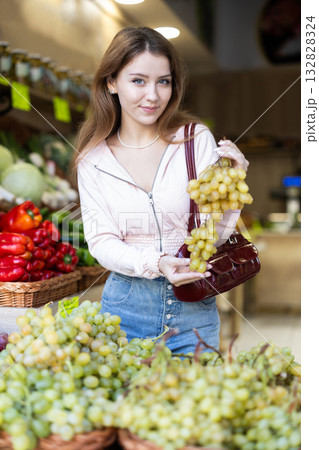 Young woman choosing ripe grapes 132828324