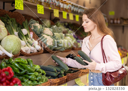 Young woman chooses cucumbers in store Young woman chooses cucumbers in store 132828330