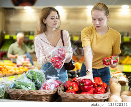 Two women choose bell peppers together Two women choose bell peppers together 132828331