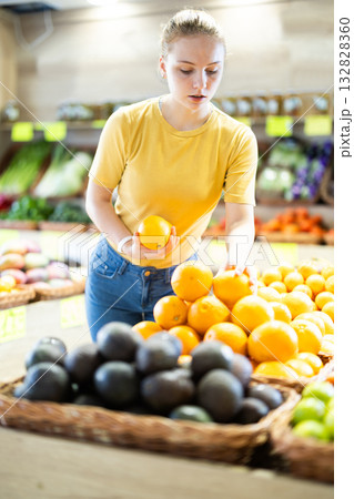 Teenage girl chooses oranges in store 132828360
