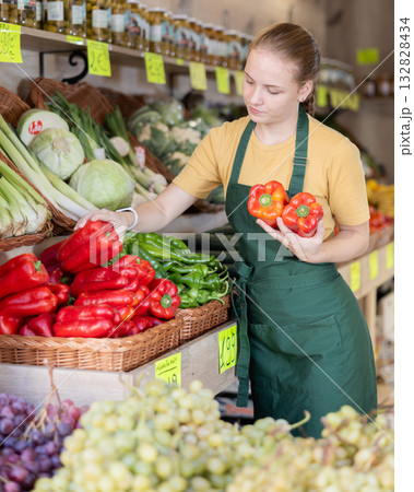 Woman employees in uniform holding fresh bell pepper in grocery shop 132828434