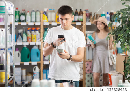 Guy buyer scans qr code on sunblock cream label, woman shopping in background Guy buyer scans qr code on sunblock cream label, woman shopping in background 132828438