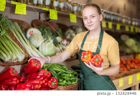 Woman employees in uniform holding fresh bell pepper in grocery shop 132828446