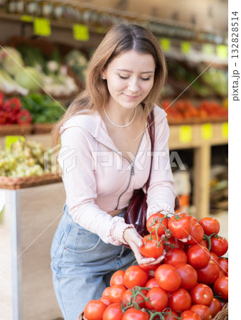 Young woman chooses tomatoes in store 132828514