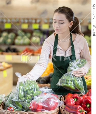 Woman seller putting green peas in a bag on the counter 132828519