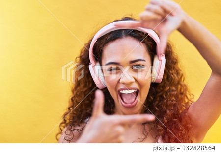 Hands, frame and portrait of woman with headphones on yellow background for profile picture. Face, female and finger framing with music for perspective, selfie and vision of happiness, smile and tech Hands, frame and portrait of woman with headphones on yellow background for profile picture. Face, female and finger framing with music for perspective, selfie and vision of happiness, smile and tech 132828564