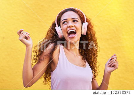 Music, idea and dance with a black woman listening to the radio outdoor on a yellow wall background. Headphones, energy and face with an attractive young female streaming audio sound for fun 132828572