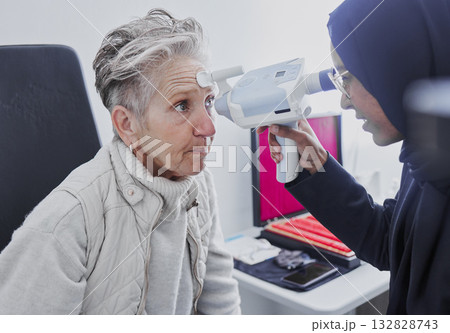 Eye exam, vision and senior woman with optometrist in clinic for eyes test, eyesight and optical assessment. Optometry, healthcare and Muslim optician and patient for glasses, lens and retinal camera Eye exam, vision and senior woman with optometrist in clinic for eyes test, eyesight and optical assessment. Optometry, healthcare and Muslim optician and patient for glasses, lens and retinal camera 132828743