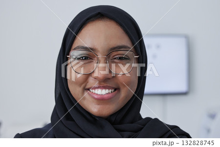Hijab, muslim woman smile and portrait in a consulting doctor office ready for eye test with chart. Healthcare, eyes wellness and proud clinic worker face from company vision and job success Hijab, muslim woman smile and portrait in a consulting doctor office ready for eye test with chart. Healthcare, eyes wellness and proud clinic worker face from company vision and job success 132828745