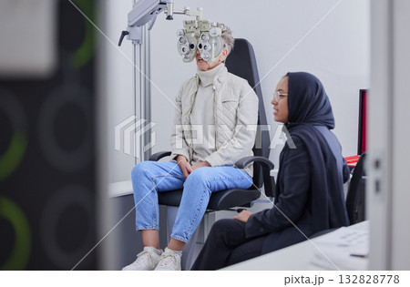 Vision, eye exam and senior woman with optometrist in clinic for testing, eyesight and optical assessment. Optometry, healthcare and Muslim optician with patient, phoropter and medical tool for eyes 132828778