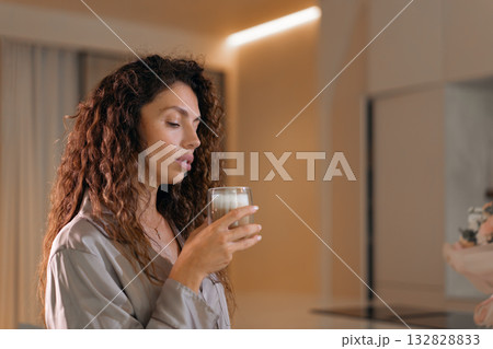 Curly haired woman in pajamas having coffee at Curly haired woman in pajamas having coffee at 132828833