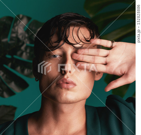 Gen z, man and portrait of a male model with hand beauty and fashion face. Isolated, green background and studio of a young person with Monstera plants for organic skincare and eco friendly style Gen z, man and portrait of a male model with hand beauty and fashion face. Isolated, green background and studio of a young person with Monstera plants for organic skincare and eco friendly style 132828886