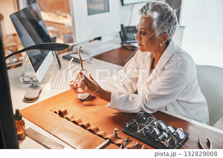 Senior optometrist woman, glasses and design for focus, vision or frame planning at desk in clinic. Elderly optician, spectacle designer and eye care in workplace for fashion, small business and goal 132829008