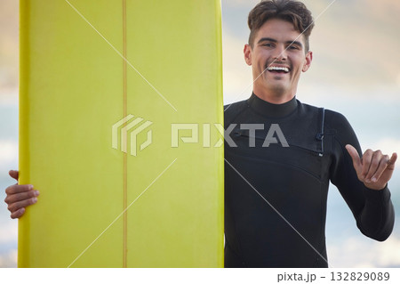 Hand sign, portrait and surfer with smile, fitness and training for wellness, balance and healthy lifestyle. Face, guy and male athlete with surfboard, freedom and happiness for adventure or vacation 132829089