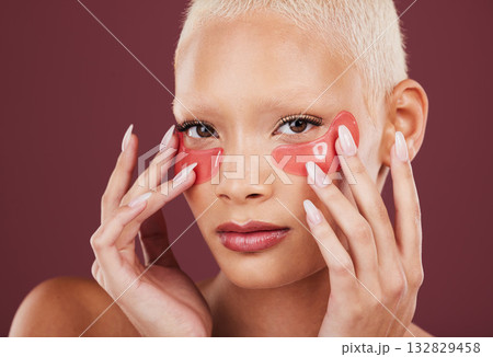 Portrait, eye mask and antiaging with a model black woman in studio on a red background for skincare. Face, skin and beauty with an attractive young female posing to promote a cosmetic product 132829458