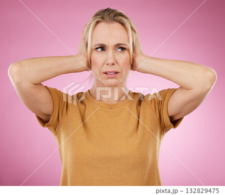 Loud, studio and woman closing her ears in a studio for noise distraction, sound or complaint. Upset, mad and annoyed female model with a hands on her head for cover isolated by a pink background. 132829475