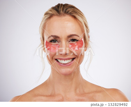 Skincare, eye pads and woman in studio with beauty, self care and natural face treatment. Cosmetic, dermatology and portrait of mature female model with anti aging facial treatment by gray background 132829492