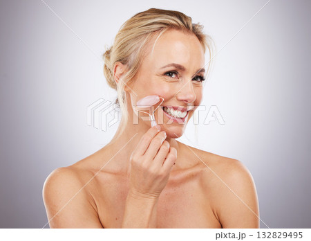 Face, massage and skincare with a mature woman in studio on a gray background for antiaging treatment. Beauty, relax and product with an attractive female massaging her skin for self care results Face, massage and skincare with a mature woman in studio on a gray background for antiaging treatment. Beauty, relax and product with an attractive female massaging her skin for self care results 132829495