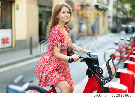 young woman stands near a bicycle rental point 132829669