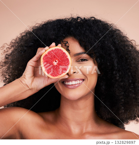 Face, hair care and portrait of black woman with grapefruit in studio isolated on a brown background. Fruit, skincare and happy female model holding food for healthy diet, nutrition and vitamin c. 132829897