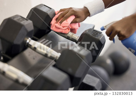 Dumbbells, cleaner and hands cleaning at a gym with liquid soap in spray bottle with cloth for wellness. Janitor or person wipes dirty bacteria on dusty weights, tools or fitness training equipment Dumbbells, cleaner and hands cleaning at a gym with liquid soap in spray bottle with cloth for wellness. Janitor or person wipes dirty bacteria on dusty weights, tools or fitness training equipment 132830013