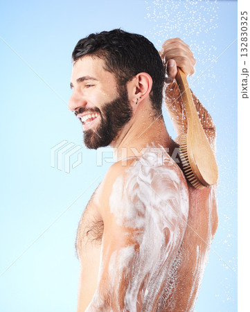 Shower, brush and man cleaning body with soap, foam and water splash for wellness, hygiene and grooming. Skincare, self care and happy male with smile, bath cosmetics and washing on blue background Shower, brush and man cleaning body with soap, foam and water splash for wellness, hygiene and grooming. Skincare, self care and happy male with smile, bath cosmetics and washing on blue background 132830325