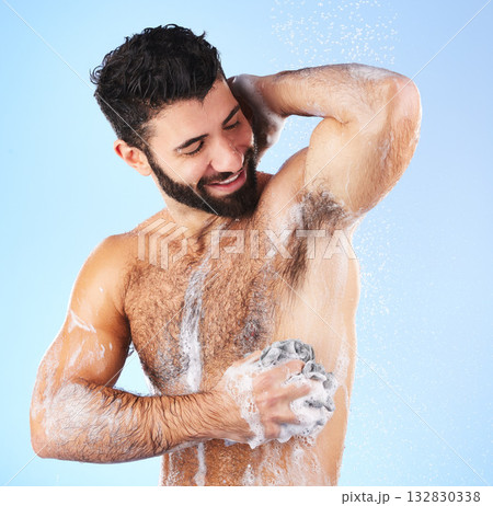 Shower, cleaning and man with sponge, soap and water splash in studio for wellness, hygiene and grooming. Skincare, health and happy male with foam, cosmetics and washing body on blue background Shower, cleaning and man with sponge, soap and water splash in studio for wellness, hygiene and grooming. Skincare, health and happy male with foam, cosmetics and washing body on blue background 132830338