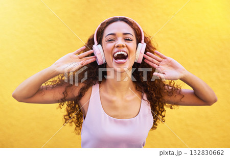 Music, portrait and laughter with a black woman listening to the radio outdoor on a yellow wall background. Headphones, energy and face with an attractive young female streaming audio sound for fun 132830662