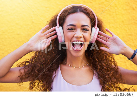 Music, freedom and portrait with a black woman listening to the radio outdoor on a yellow wall background. Headphones, energy and face with an attractive young female streaming audio sound for fun 132830667