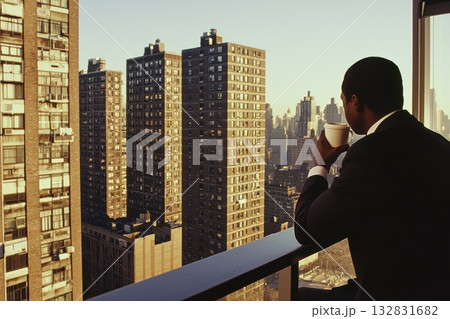 Businessperson Enjoying Coffee on Balcony with Cityscape View in Early Morning Light 132831682