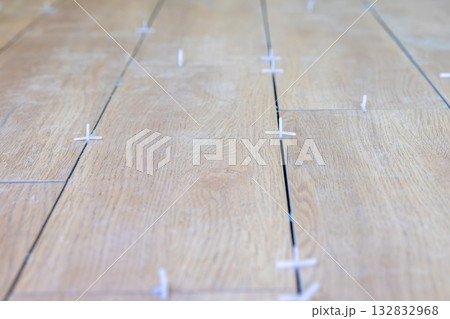 Tiler use plastic tile spacers for accurate alignment of floor tiles, Semi-dry floor screed. 132832968