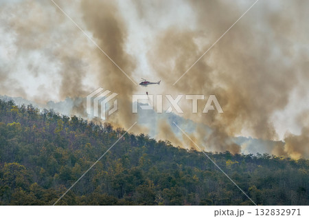 Fire fighting helicopter carry water bucket to extinguish the forest fire. Fire fighting helicopter carry water bucket to extinguish the forest fire. 132832971