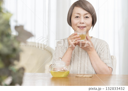 夏リビングで冷茶を飲むシニア女性 夏リビングで冷茶を飲むシニア女性 132833432