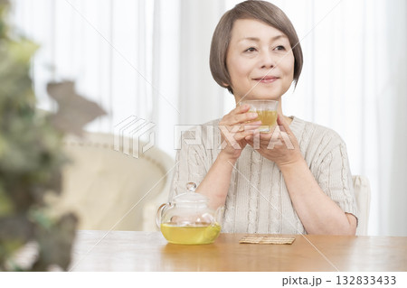 夏リビングで冷茶を飲むシニア女性 夏リビングで冷茶を飲むシニア女性 132833433